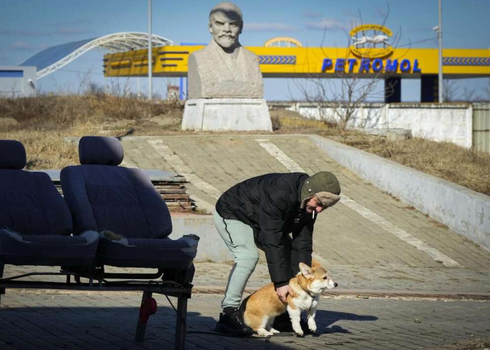 A local resident plays with a dog in front of a statue of former Soviet leader Vladmir Lenin, in Comrat, Moldova, Saturday, March 12, 2022. Across the border from war-engulfed Ukraine, tiny, impoverished Moldova, an ex-Soviet republic now looking eagerly Westward, has watched with trepidation as the Russian invasion unfolds. In Gagauzia, a small, autonomous part of the country that\’s traditionally felt closer to the Kremlin than the West, people would normally back Russia, which they never wanted to leave when Moldova gained independence. (AP Photo/Sergei Grits)