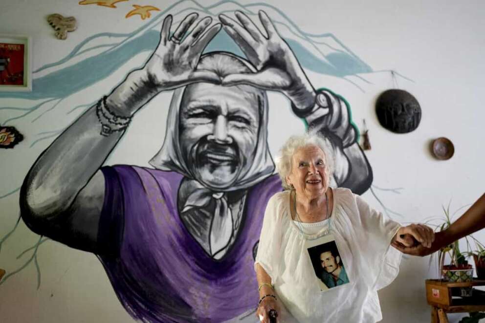 Nora Cortinas, 94, poses for a portrait wearing a photo of her disappeared son Gustavo at her home, decorated with a mural of her, on the outskirts of Buenos Aires, Argentina, Monday, Jan. 29, 2024. Cortinas became one of many mothers whose children were kidnapped by the state when Gustavo disappeared on April 15, 1977, giving birth to what is today’s human rights organization, the Mothers of Plaza de Mayo. (AP Photo/Natacha Pisarenko)
