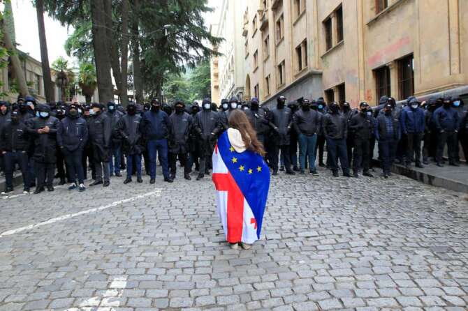 A demonstrator with draped Georgian national and EU flags stands in font of police blocking the way to the Parliament building, during an opposition protest against “the Russian law” in the center of Tbilisi, Georgia, Tuesday, May 14, 2024. Georgia’s parliament on Tuesday began the third and final reading of a divisive bill that sparked weeks of mass protests, with critics seeing it as a threat to democratic freedoms and the country’s aspirations to join the European Union. (AP Photo/Shakh Aivazov