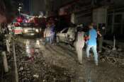 People walk near the building that was hit by an Israeli airstrike in the southern suburbs of Beirut, Lebanon, Tuesday, July 30, 2024. An Israeli airstrike hit Hezbollah’s stronghold south of Beirut Tuesday evening causing damage, a Hezbollah official and the group’s TV station said. (AP Photo/Hussein Malla)