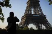 A man takes photographs of the Olympic rings mounted on the Eiffel Tower Friday, June 7, 2024 in Paris. The Paris Olympics organizers on Friday unveiled a display of the five Olympic rings mounted on the Eiffel Tower as the French capital marks 50 days until the start of the Summer Games. (AP Photo//Thomas Padilla)