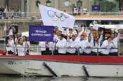 Athletes of the Refugee Olympic Team wave aboard a boat in the floating parade on the Seine River in Paris, France, during the opening ceremony for the 2024 Summer Olympics, Friday, July 26, 2024. (Nir Elias/Pool Photo via AP)