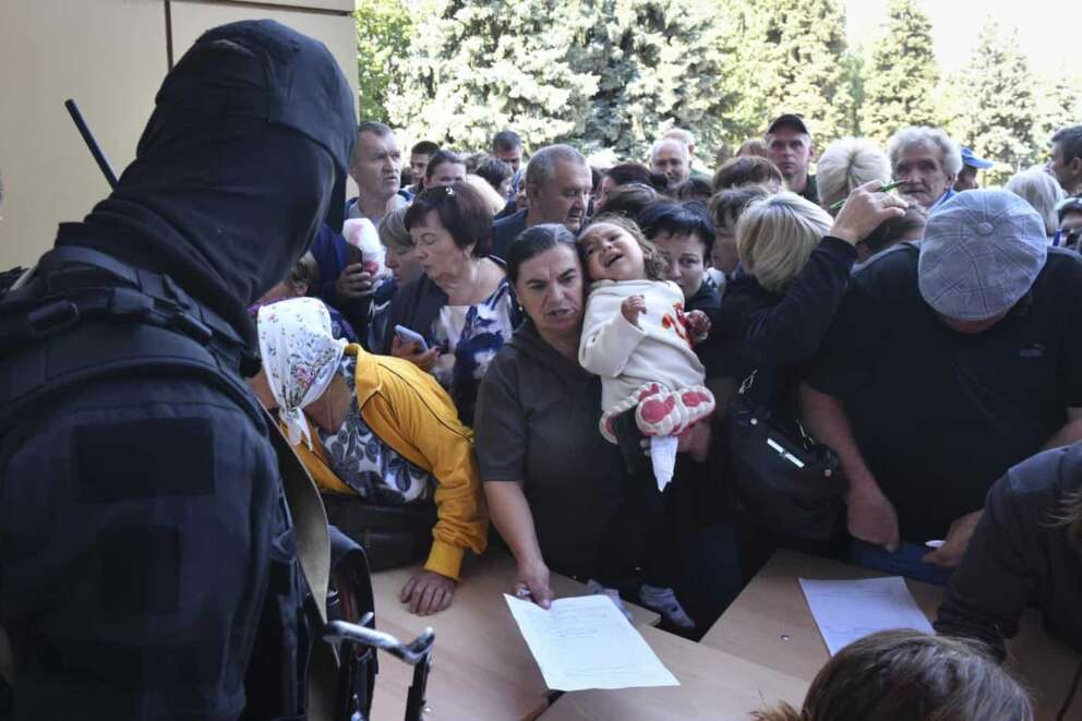 Evacuated people in the Kursk region queue to fill out the form for humanitarian aid at a humanitarian aid distribution center in Kursk, Russia, Wednesday, Aug. 14, 2024. (AP Photo)