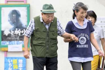 Iwao Hakamada, left, 88-year-old former boxer who has been on death row for nearly six decades after his murder conviction that his lawyers said was based on forced confession and fabricated evidence, is helped by a supporter as he goes for a walk in Hamamatsu, Shizuoka prefecture, central Japan Wednesday, Sept. 25, 2024. (Kyodo News via AP)