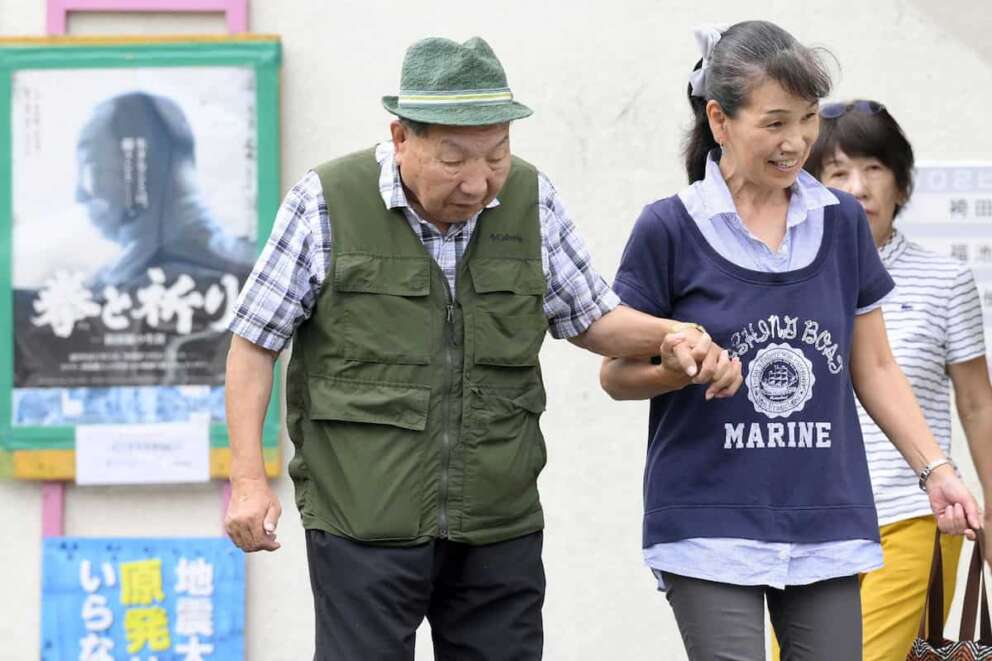 Iwao Hakamada, left, 88-year-old former boxer who has been on death row for nearly six decades after his murder conviction that his lawyers said was based on forced confession and fabricated evidence, is helped by a supporter as he goes for a walk in Hamamatsu, Shizuoka prefecture, central Japan Wednesday, Sept. 25, 2024. (Kyodo News via AP)